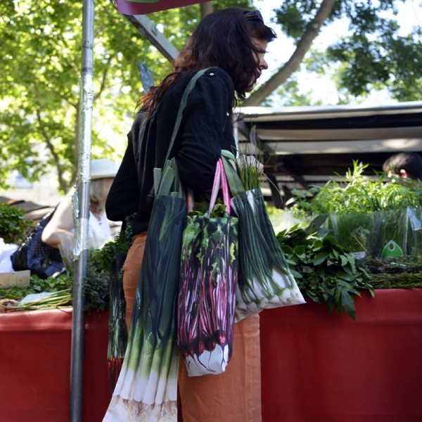 Young woman at the street market with shopping bags of vegetables leeks, beets and onions. French reusable bags Young woman at the street market with shopping bags of vegetables leeks, beets and onions. French reusable bags