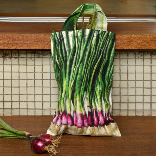 Sac à ciboules avec légumes posé sur un plan de travail de cuisine. Sac de course légume Maron Bouillie fabriqué en France.