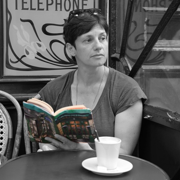 Femme assise en terrasse avec un livre recouvert du protège livre en tissu café de Paris Au petit fer à cheval de Maron Bouillie