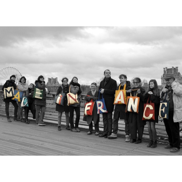 12 people on the pont des arts in Paris each carrying an initial bag forming the words MADE IN FRANCE - Maron Bouillie