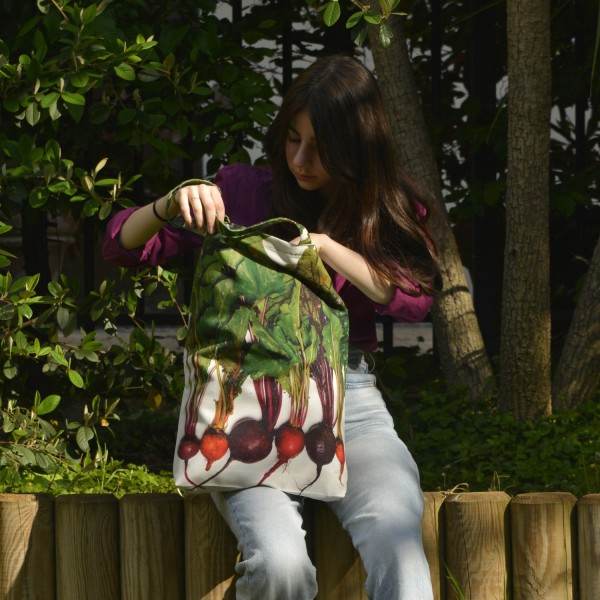 Jeune fille assise dans un jardin avec le Sac de shopping légumes betteraves multicolores de Maron Bouillie. Jeune fille assise dans un jardin avec le Sac de shopping légumes betteraves multicolores de Maron Bouillie.
