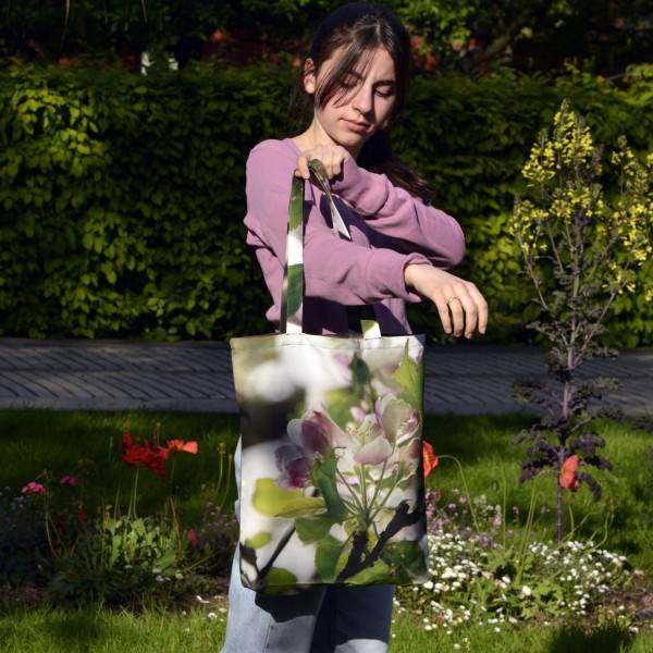 Young girl in a garden wearing the Apple Tree Flower Tote Bag by Maron Bouillie Made in France