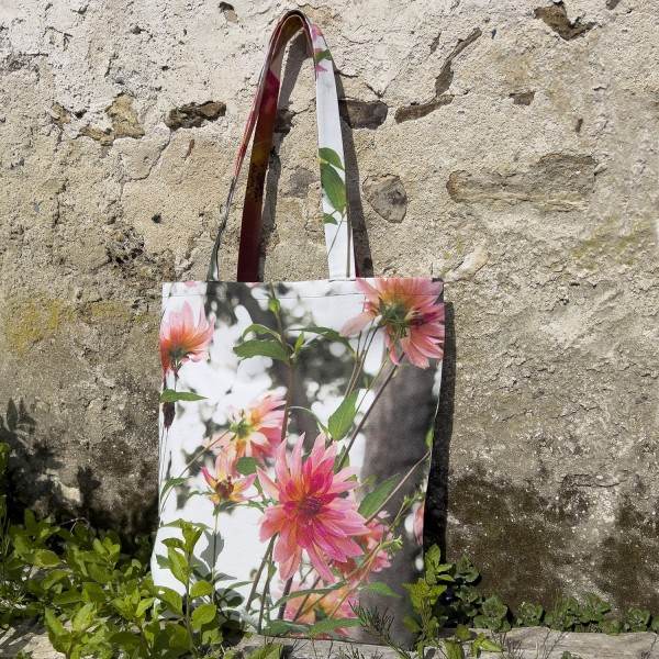 Sac fleuri modèle Dahlia posé devant un mur en pierre - Tote bag en tissu de Maron Bouillie made in France
