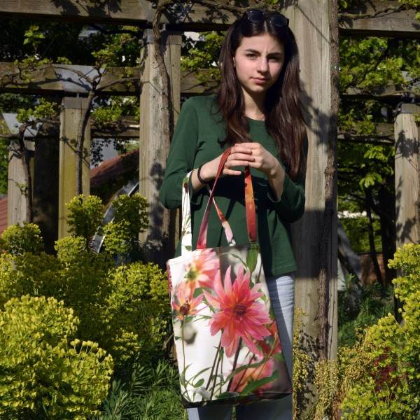 Young girl in a garden wearing the Dahlia Flower Tote Bag by Maron Bouillie Made in France