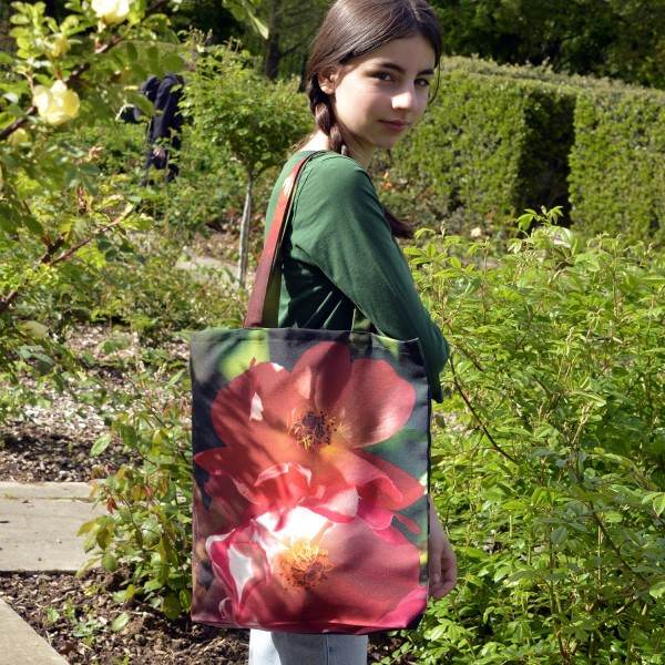 Young girl in a garden wearing the Roses de France Flower Tote Bag by Maron Bouillie Made in France Young girl in a garden wearing the Roses de France Flower Tote Bag by Maron Bouillie Made in France