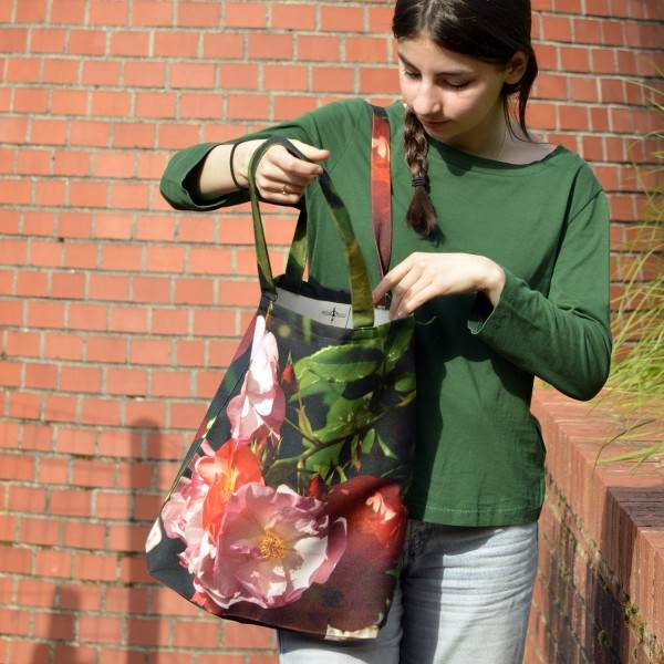 Jeune fille devant un mur en brique avec le tote bag fleuri modèle Roses de Maron Bouillie made in France