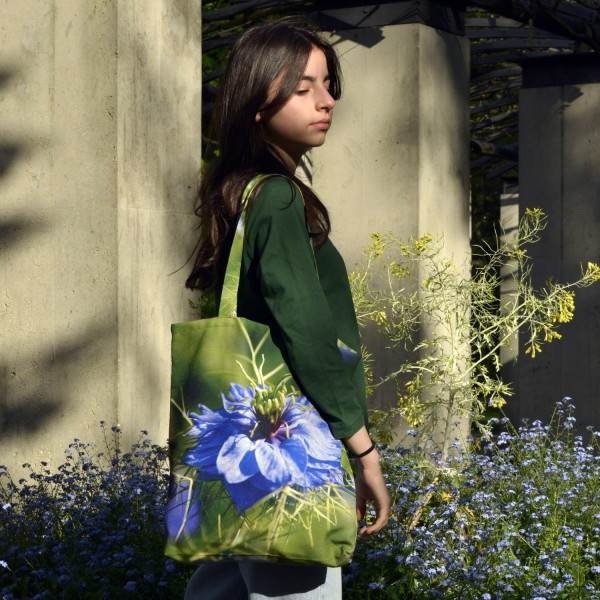 Young girl in a garden wearing the Damascus Nigella Flower Tote Bag by Maron Bouillie Made in France