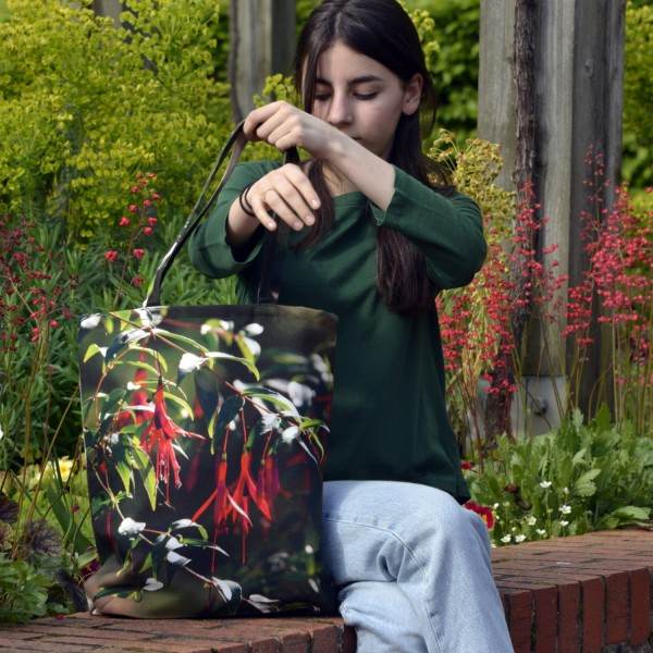 Jeune fille assise dans un jardin portant le sac fleur modèle Fuchsia Royal de Maron Bouillie - made in France