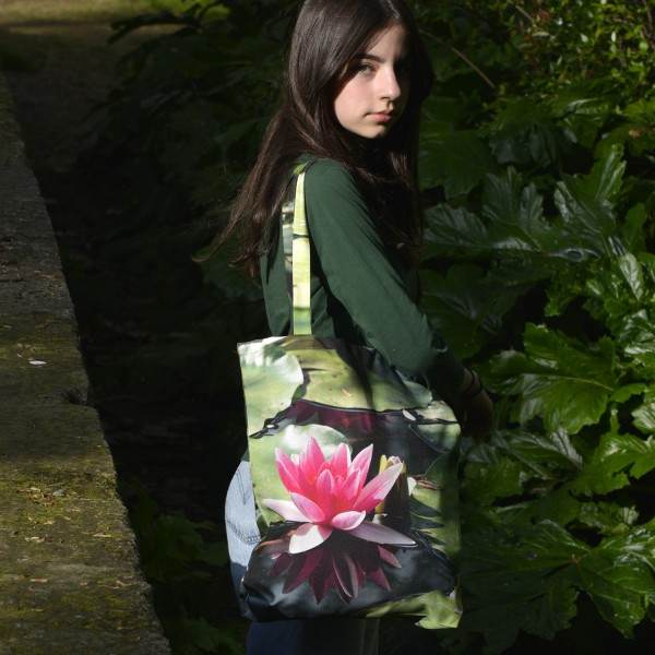 Jeune fille dans un jardin avec le tote bag fleuri modèle Nénuphar de Maron Bouillie made in France