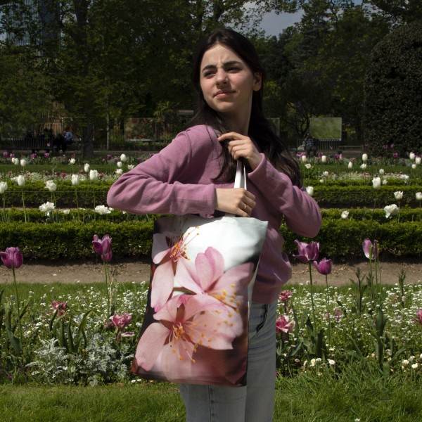 Jeune fille dans un jardin portant le tote bag fleuri modèle Cerisier d’Hiver de Maron Bouillie made in France