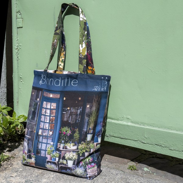 Tote bag design Fleuriste Brindille Paris, posé devant une porte verte, Maron Bouillie made in France