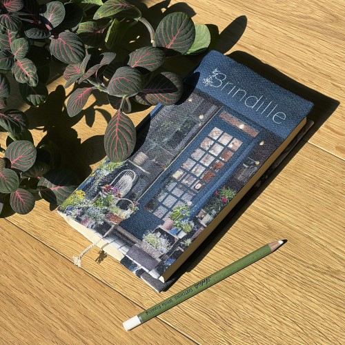 Paris Florist Brindille paperback book cover placed on a table with a plant - Maron Bouillie, made in France