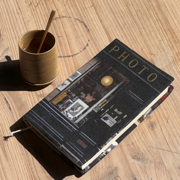 Protège-livre Paris Photographie posé sur une table avec un café dans une tasse en bois - Maron Bouillie made in France