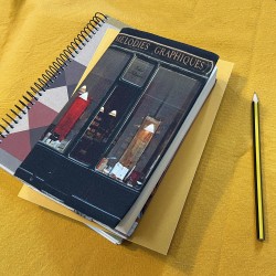 Protège-livre Paris Boutique Mélodies graphiques Calligraphies posé sur une table jaune avec un café - Maron Bouillie 2