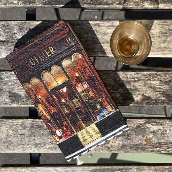 Protège-livre de poche Luthier de Paris posé sur une table de café - Maron Bouillie made in France