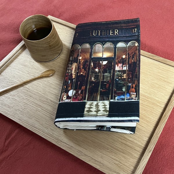 Couverture de livre en tissu Luthier de Paris posé sur un plateau en bois sur un fond rouge  - Maron Bouillie made in France