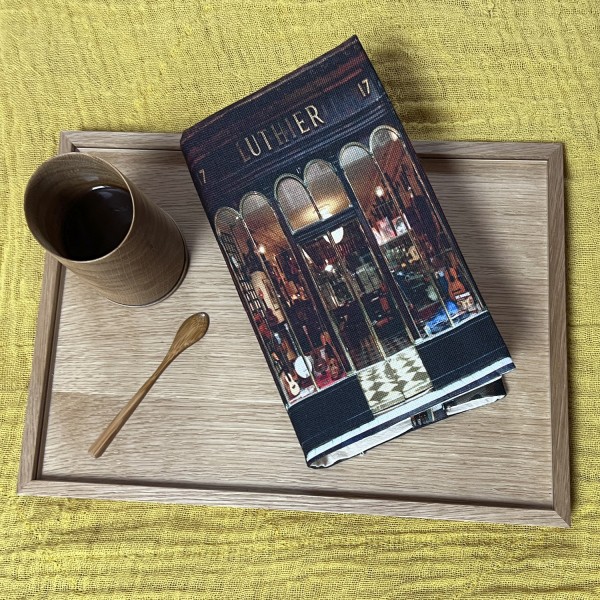 Couvre-livre de poche Luthier de Paris posé sur un plateau en bois avec un café - Maron Bouillie made in France