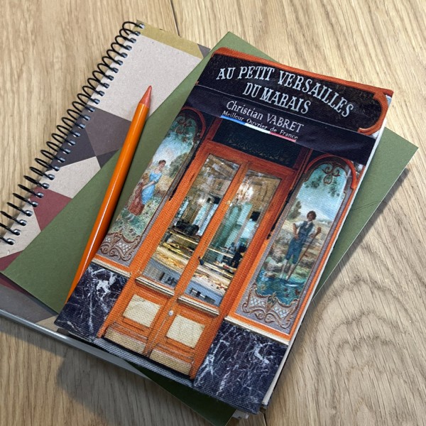 Paris Boulangerie Au Petit Versailles du Marais fabric book cover placed on a table with notebooks - Maron Bouillie Paris Boulangerie Au Petit Versailles du Marais fabric book cover placed on a table with notebooks - Maron Bouillie