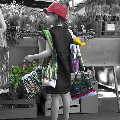 Little girl in front of a street market stall carrying Maron Bouillie's vegetable bags